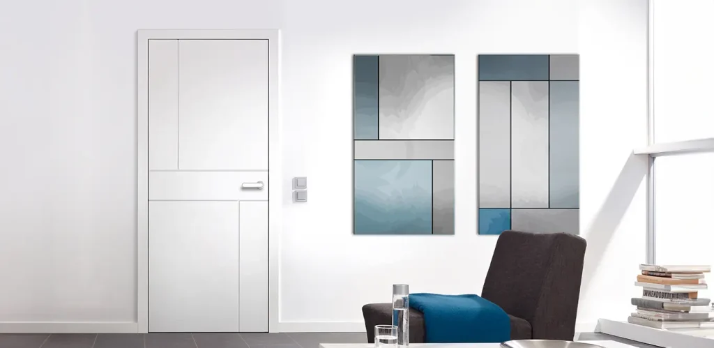 Ein modernes Interieur mit einer weißen Tür, inspiriert von Türinspirationen, einem grauen Boden, einem abstrakten Triptychon an der Wand und einer Ecke eines schwarzen Stuhls mit blauem Kissen.