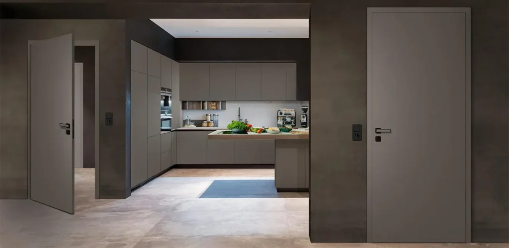 Eine moderne Küche mit grauen Schränken, CPL-Türen, integrierten Geräten und einer zentralen Insel mit frischem Gemüse auf der Arbeitsplatte.