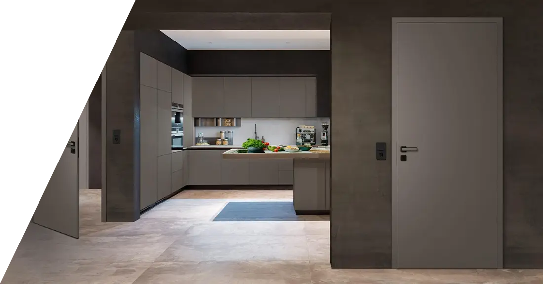 Eine moderne Küche mit grauen Schränken aus CPL-Türen und Einbauleuchten, gesehen von einem angrenzenden Raum mit polierten Betonböden.