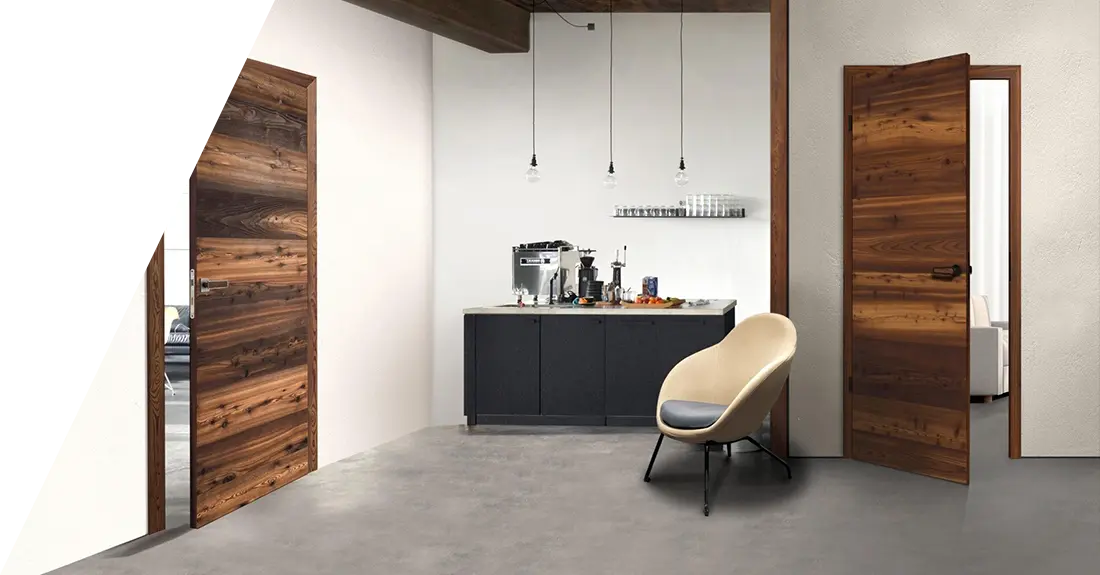 Moderne Kücheneinrichtung mit Echtholztüren, grauem Boden und einer zentralen Insel mit Kaffeemaschine und verschiedenen Geräten, ergänzt durch einen einzelnen beigen Stuhl und Pendelleuchten.