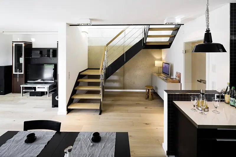 Moderne Küche mit offenem HPL-Treppen, hellem Holzboden und schwarzen Akzenten.