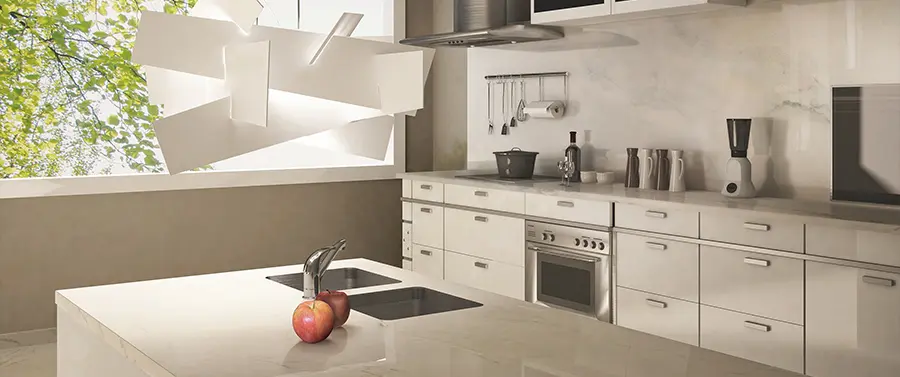 Ein moderner Küchenstil mit beigen Schränken, Küchengeräten aus Edelstahl und einer Mittelinsel mit einer Obstschale, in der sich ein Apfel befindet.