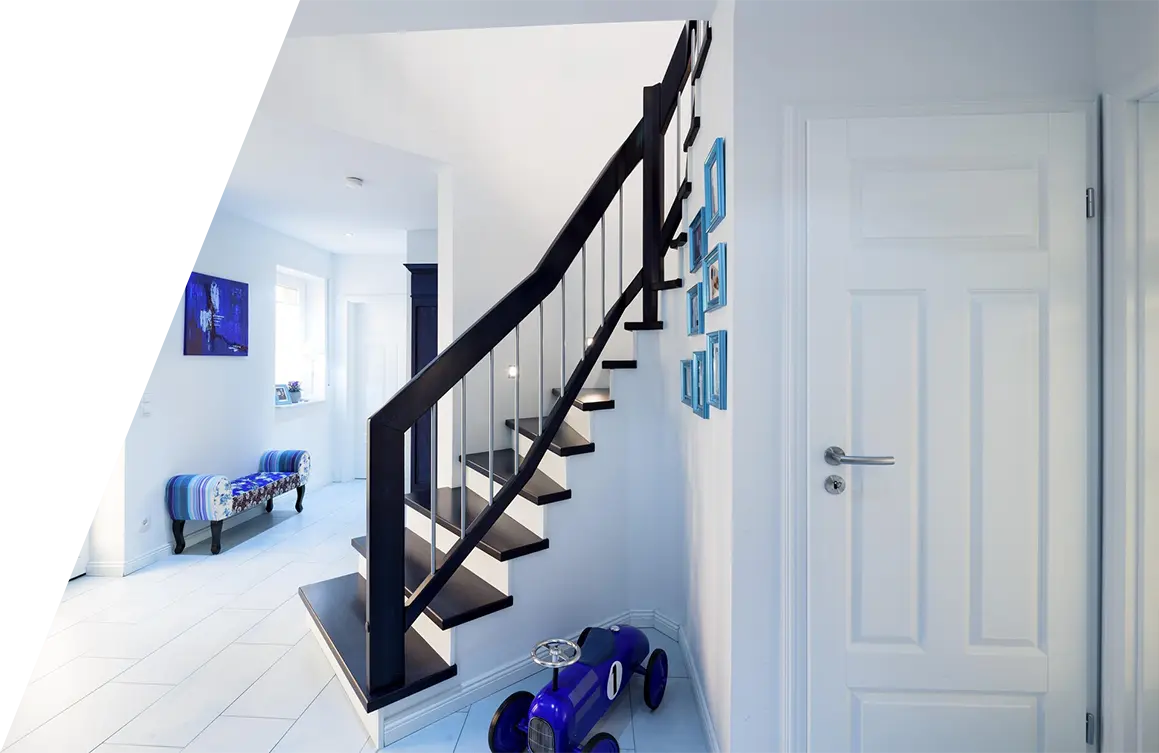 Eine moderne Wohneinrichtung mit einer Treppe mit schwarzem Geländer, einem hellen Flur, weißen Wänden und dekorativen blauen Akzenten, inspiriert von Treppeninspirationen.