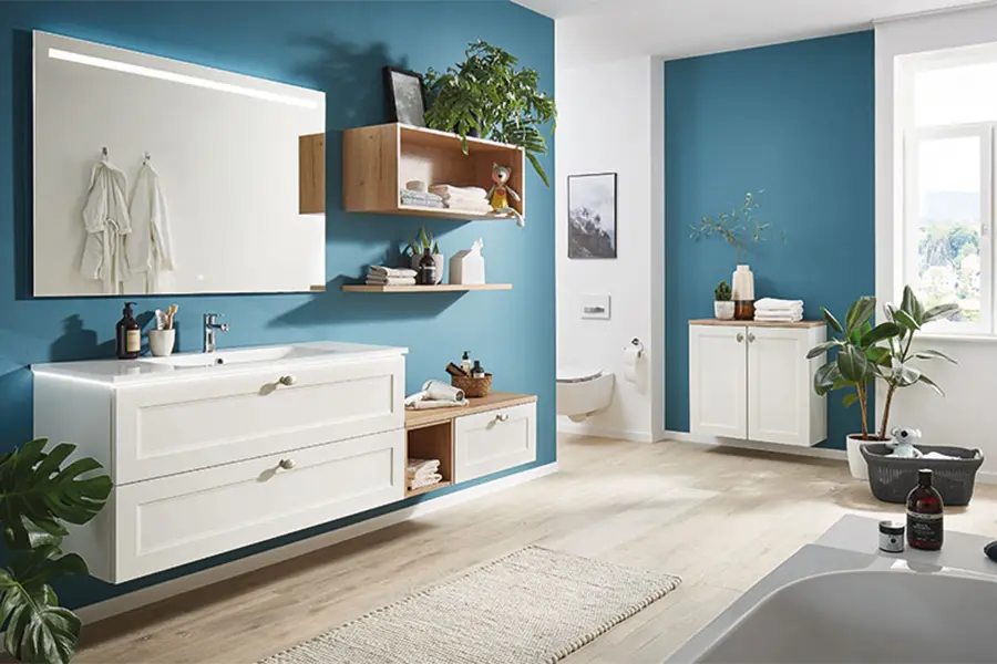 Eine moderne Badeinrichtung mit weißem und Holz-Finish, blau gestrichenen Wänden und einem großen Spiegel über einem weißen Waschtisch.