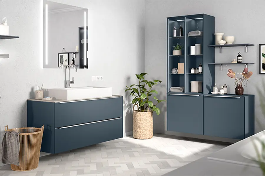Eine moderne Badeinrichtung mit blauen Schränken, weißen Arbeitsplatten und einer Topfpflanze zur Dekoration.