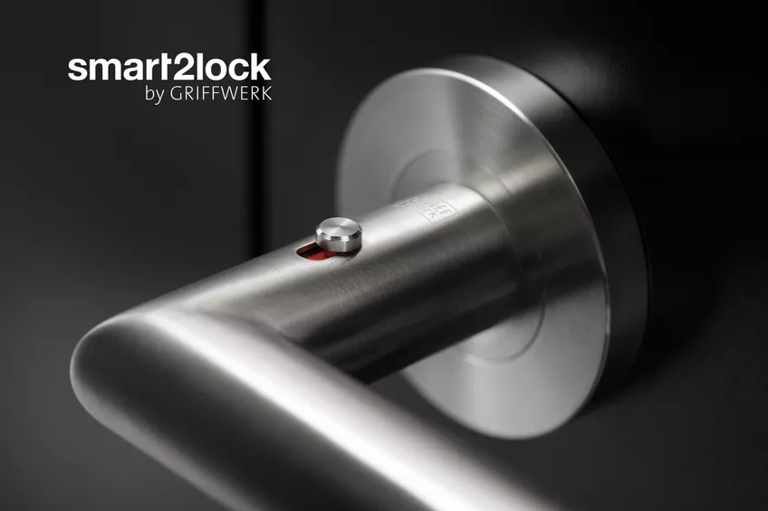 Ein moderner Türgriff mit integriertem elektronischem Schließsystem, gebrandet als „smart2lock by griffwerk“, installiert an einer dunklen Tür mit Fokus auf den Schließmechanismus.
