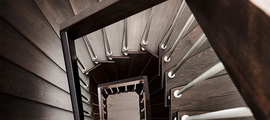 Ein symmetrischer Blick von oben auf eine freitragende Treppe mit Metallgeländern, die einen visuellen Effekt von Tiefe und Wiederholung erzeugt.