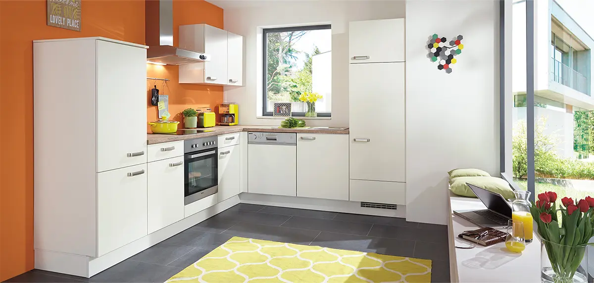 Eine moderne Küche mit weißer Einrichtung, Edelstahlgeräten und Akzenten in Gelb und Grün.