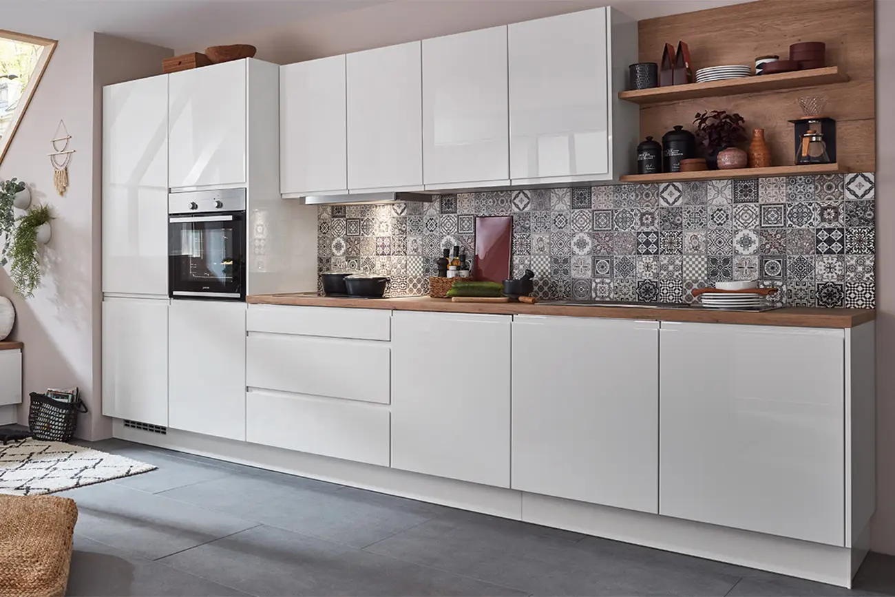 Moderne Küchenformen mit weißen Schränken, gemusterter Rückwand und Geräten aus Edelstahl.