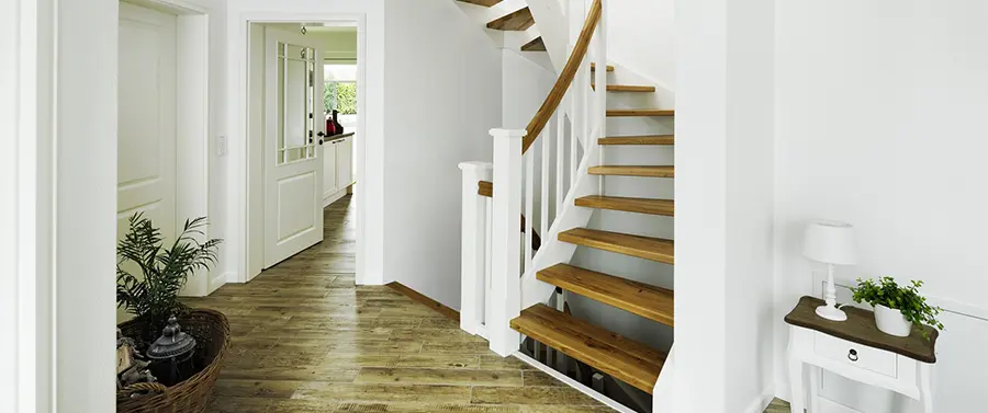 Ein heller Flur mit Treppen mit weißen Setzstufen, Hartholzboden und Topfpflanzen, der zu einem gut beleuchteten Raum führt.