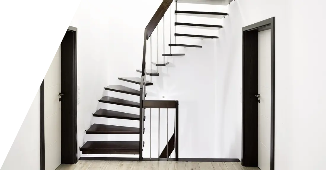 Ein moderner Treppengarten mit schwarzen Stufen und einem minimalistischen Metallgeländer führt an einer weißen Wand zwischen zwei Türen empor.