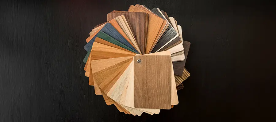 Ein Fächer aus Holzfurniermustern mit verschiedenen Holzmaserungsmustern und -farben, passend für Innenräume, auf dunklem Hintergrund.