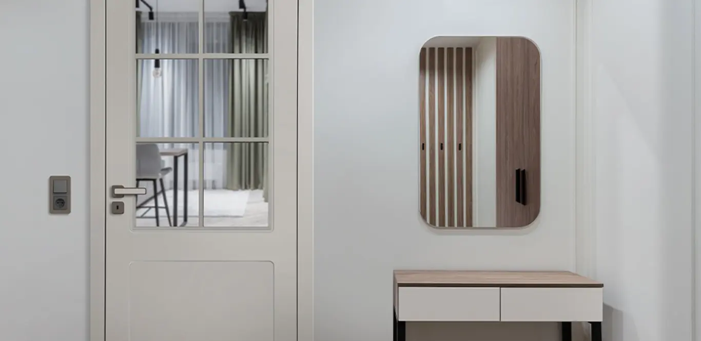 Ein minimalistischer Eingangsbereich mit einer weißen Tür mit Glasscheiben auf der linken Seite, die für Türinspirationen sorgt, und einem modernen, an der Wand montierten Konsolentisch aus Holz mit einer Schublade auf der rechten Seite.