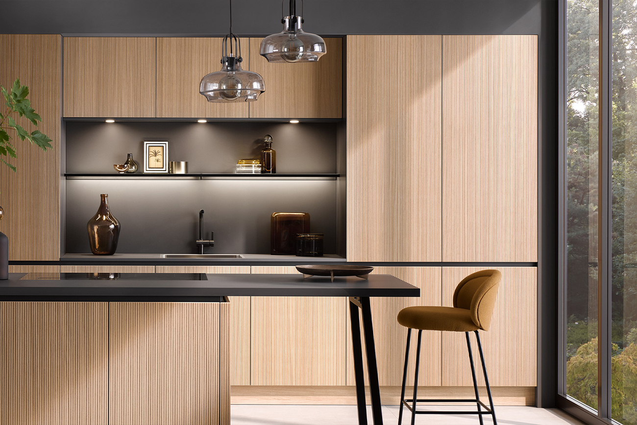 Ein modernes Design-Küchen-Interieur mit Holzschränken, einer eleganten schwarzen Arbeitsplatte und Pendelleuchten, einem integrierten Waschbecken und einem stilvollen Barhocker.