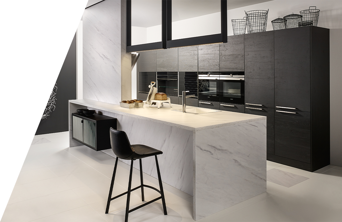 Eine moderne Küche mit einer Marmor-Kücheninsel, schwarzen Einbauschränken und eingebauten Küchengeräten im Küchenstil.