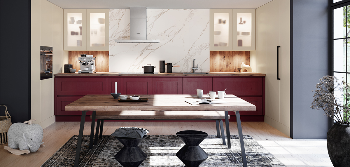 Moderne Landhausküchen mit burgunderroten Schränken, Marmorrückwand und einem hölzernen Esstisch mit Utensilien und Geschirr.